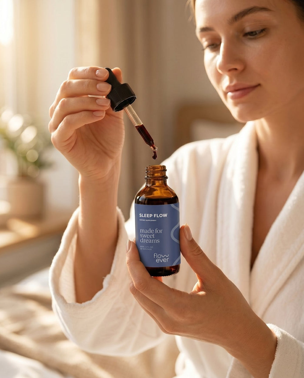 Woman in a white robe holding a bottle of Flowever Sleep Flow with a dropper